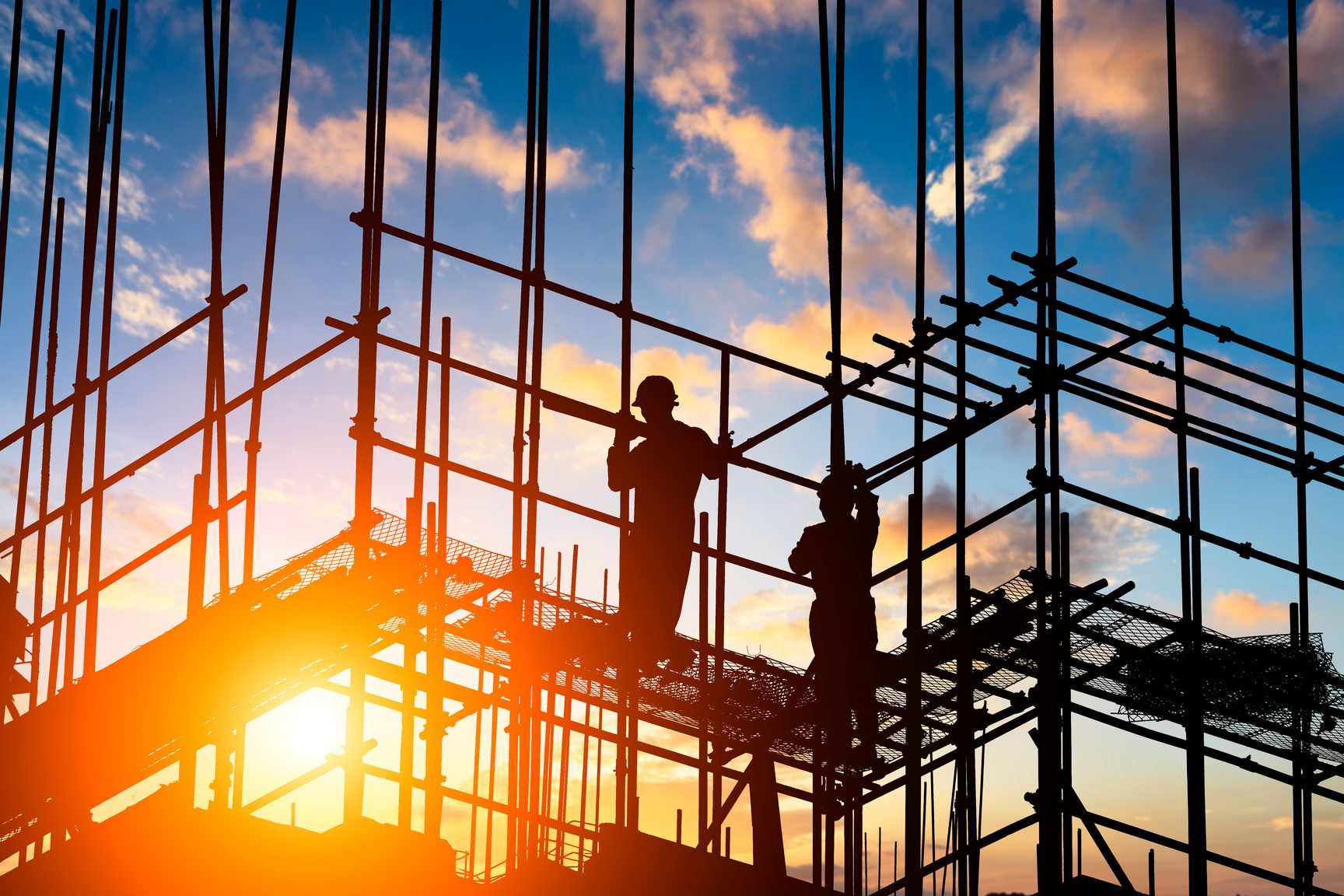 Workers on steel rebar structure at sunset
